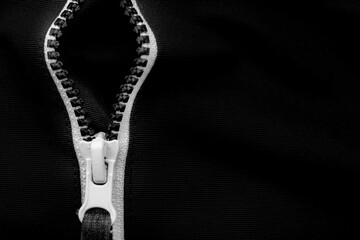 White lock with a zipper on clothes, jacket, jacket close-up on a black background. Lightning.