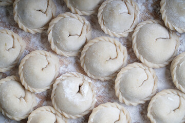 Meat or vegeterian dumplings, pelmeni on a wooden board. Russian national food. Close up top view.
