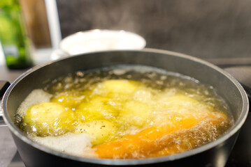 Pot of boiling water in which potatoes and carrots are boiled. close up