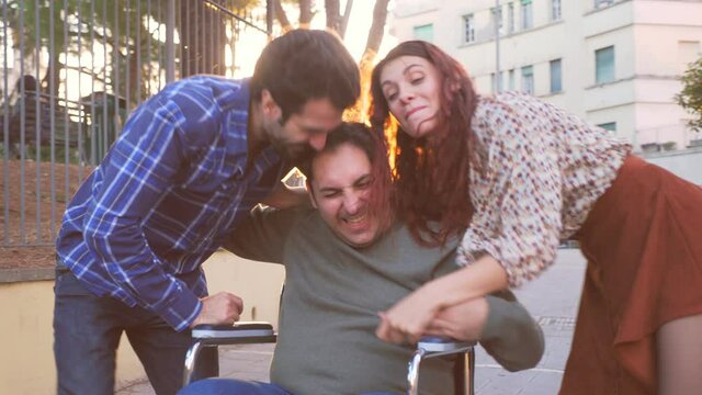 slow motion on young man with disability using wheelchair having fun with his friends who make him dance