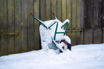Wheelbarrow at a wall in snow.