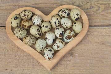 Quail egg in a heart shape on wooden background