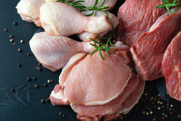 Various types of fresh meat: pork, beef, and chicken on a black table