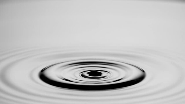 A single drop of water falling into a pool of water in slow motion.