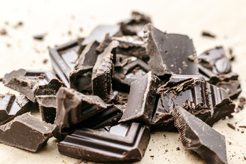 Broken to pieces dark chocolate, crushed and powder pieces. Close up view, macro photo