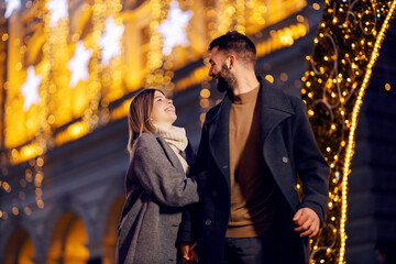 Christmas people walking on the street on New Year's eve. A happy couple in love holding hands and...