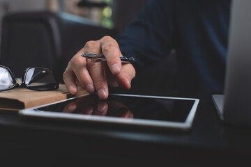 Man using digital tablet and working on laptop computer at home office