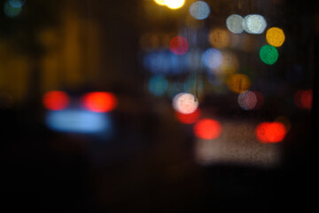 Lights of cars driving in evening city. Defocused headlights and taillights. Bokeh circles of cars in night. Blurred city traffic background
