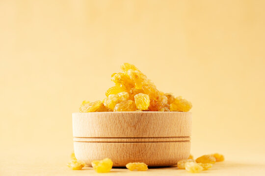 Bowl with dried golden raisins on brown. Healthy nutrition with fruits. High quality photo