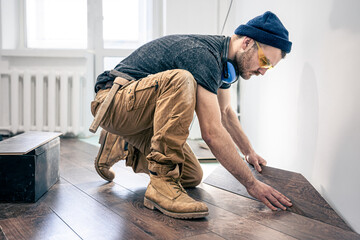 A male worker puts laminate flooring on the floor.