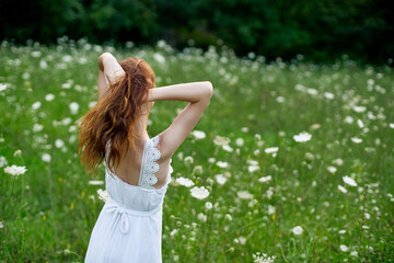 Naklejka na ściany i meble Woman in white dress in a field of flowers walk freedom