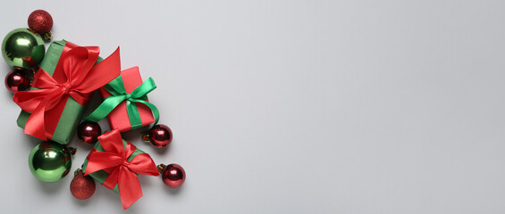 Christmas gifts and beautiful balls on light background with space for text