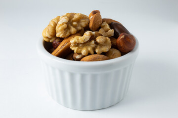 Small portion of roasted chestnuts and walnuts, in a white ceramic pot