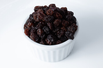 Portion of dried dark raisins in a white ceramic pot