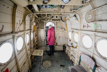 The woman is standing in an old, abandoned plane