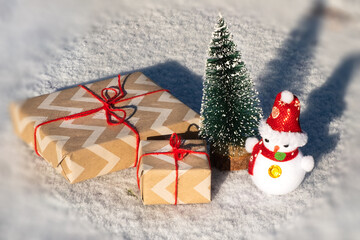 New Year gifts box and a little snowman under the tree in the snow
