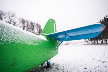 An old, abandoned plane in green and blue on a snowy winter day