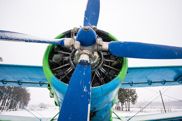 An old, abandoned plane in green and blue on a snowy winter day