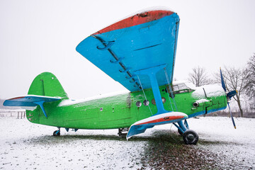 An old, abandoned plane in green and blue on a snowy winter day