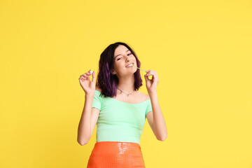 Young woman with chewing gums on yellow background