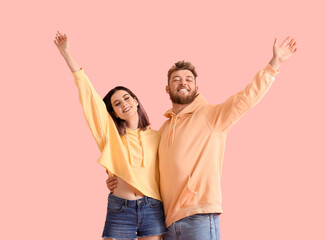 Fototapeta premium Cool happy young couple in hoodies on color background