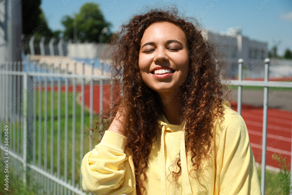 Poster Beautiful young African-American woman in stylish hoodie outdoors