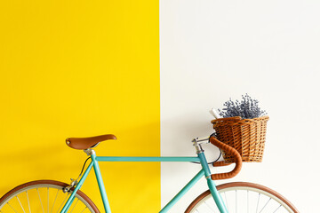 Stylish bicycle with wicker basket, newspaper and lavender flowers near color wall