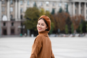 Beautiful smiling woman in beret hat on city street