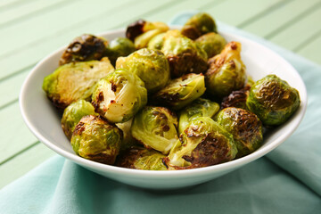 Bowl with tasty roasted Brussels cabbage on table, closeup