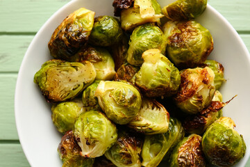 Bowl with tasty roasted Brussels cabbage on table, closeup