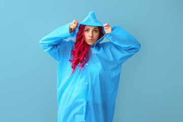 Funny woman with bright hair wearing raincoat on color background