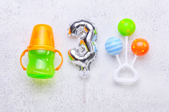 Silver Balloon In Shape Of Figure 3, Baby Bottle And Rattle On Light Background