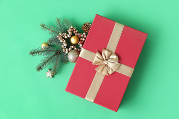 Christmas gift box with balls and fir branch on green background