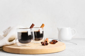 Glasses of tasty coffee with cinnamon on light background