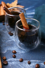 Glasses of tasty coffee with cinnamon on blue background