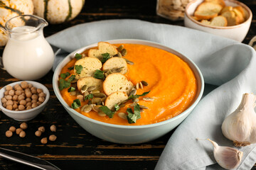 Bowl with delicious pumpkin cream soup on dark wooden table
