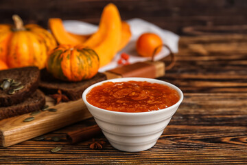 Bowl of sweet pumpkin jam on wooden background