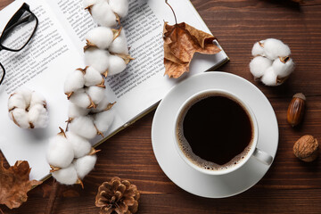 Obraz na płótnie Canvas Cup of coffee, opened book, eyeglasses, cotton flowers and autumn decor on wooden background