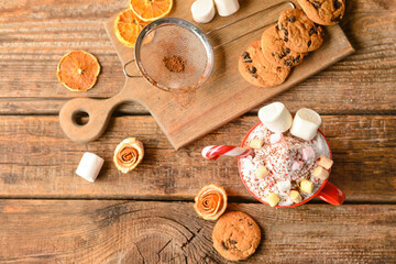 Fototapeta na wymiar Cup of tasty cacao with marshmallows and candy cane on wooden background