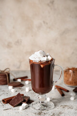 Glass cup of tasty hot chocolate with marshmallows on light background