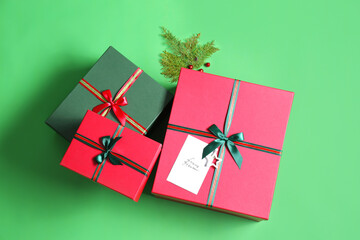 Beautiful Christmas gift boxes with greeting card on green background