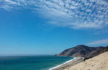 Scenic Point Mugu and Thornhill Broome Beach seen from Sandy Dune vista under beautiful sunny cumulus cloudscape in Southern California