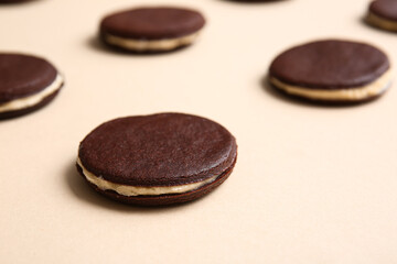 Obraz na płótnie Canvas Tasty chocolate cookies with cream on beige background, closeup