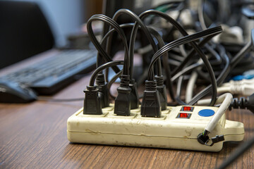 Old and damaged electric adapter power plug has many appliances are plugged outlet socket concept...