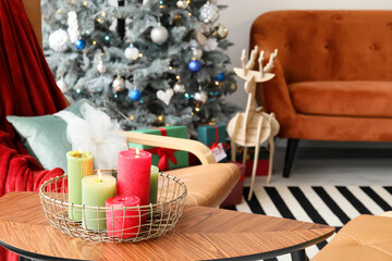 Basket with burning candles on table in living room decorated for Christmas, closeup