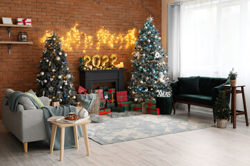 Interior of festive living room with Christmas trees, decorative mantelpiece and sofas
