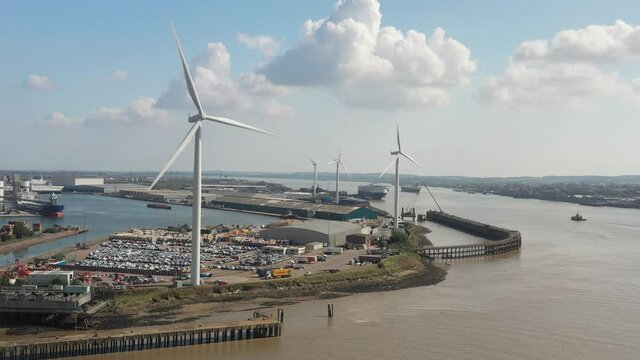 flying through wind turbine generating sustainable electricity. Harbour in background