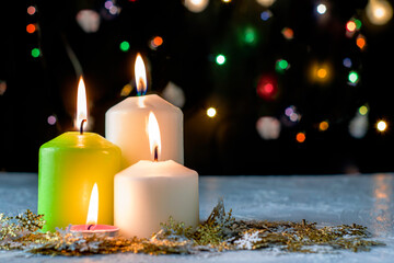 Obraz na płótnie Canvas black Christmas background with colorful lights burning candles and decorative snowflakes in the foreground