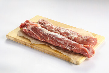 Raw pork tenderloin over board