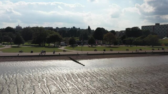 /shore at low tide. Uncovered muddy river bottom. People relaxing on waterfront. Gravesend, UK